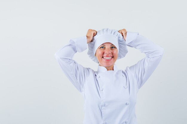 Chef de femme en uniforme blanc tenant les mains sur la tête et à la recherche de plaisir