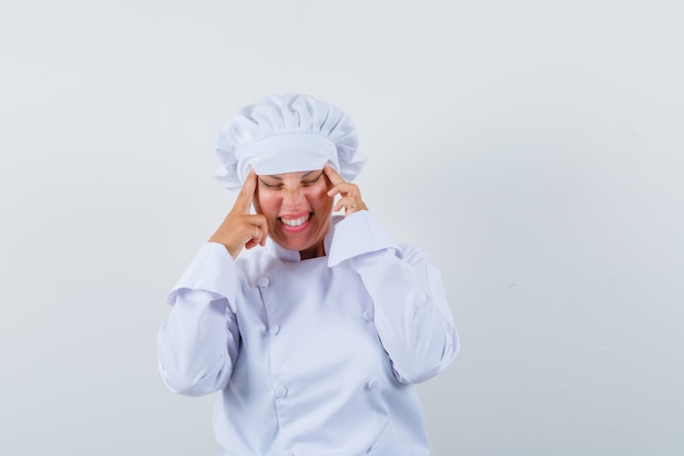 Chef de femme en uniforme blanc tirant la peau sur ses tempes et à la fatigue