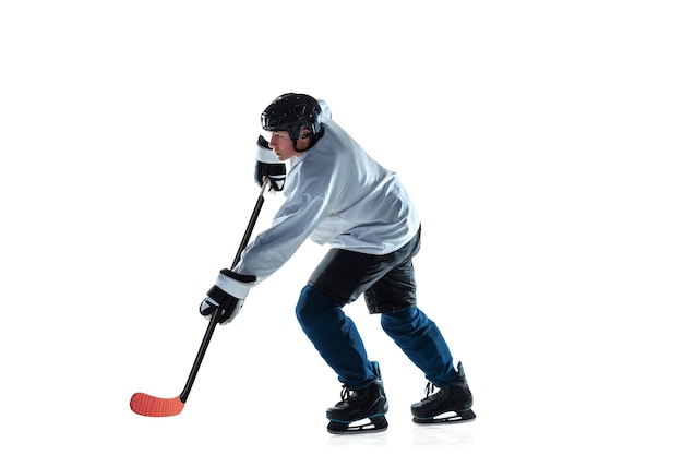 Chef. Jeune joueur de hockey masculin avec le bâton sur le court de glace et le fond blanc. Sportif portant un équipement et un casque pratiquant. Concept de sport, mode de vie sain, mouvement, mouvement, action.