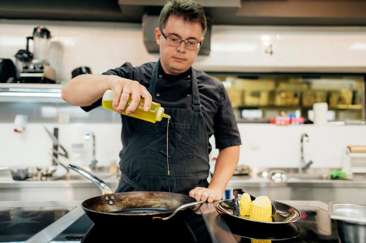 Photo gratuit chef masculin ajoutant de l'huile dans la poêle
