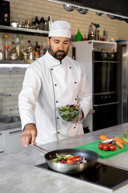 Photo gratuite chef masculin dans la cuisine faisant cuire le plat dans une poêle à frire