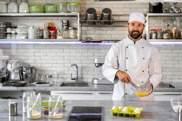 Chef masculin dans la cuisine utilisant des oeufs pour cuisiner