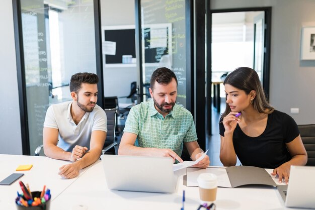 Chef masculin discutant de documents au bureau sur le lieu de travail