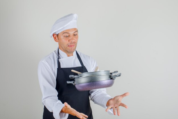 Chef masculin essayant d'attraper un pan volant en uniforme, tablier et chapeau et à la peur