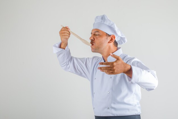 Chef masculin essayant de repas en uniforme, tablier et chapeau et à la confiance