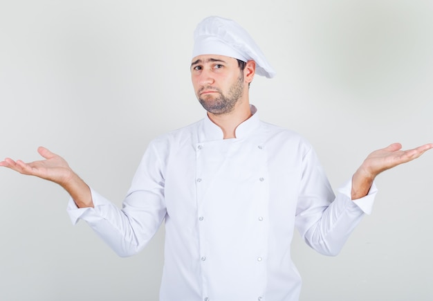 Chef masculin montrant un geste impuissant en uniforme blanc et à la confusion