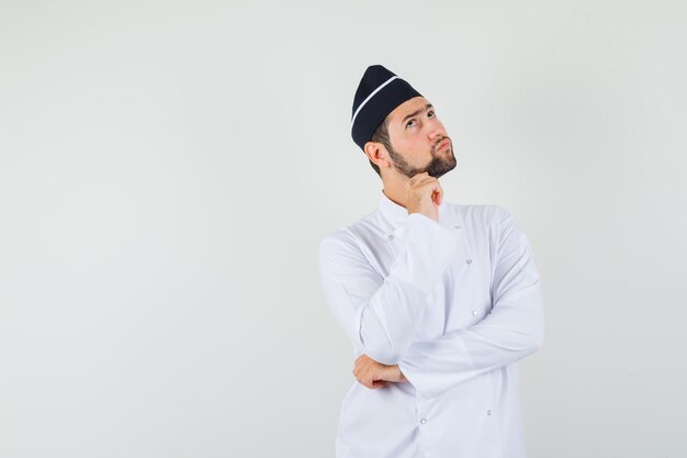 Chef masculin recherchant en uniforme blanc et pensif, vue de face. espace pour le texte