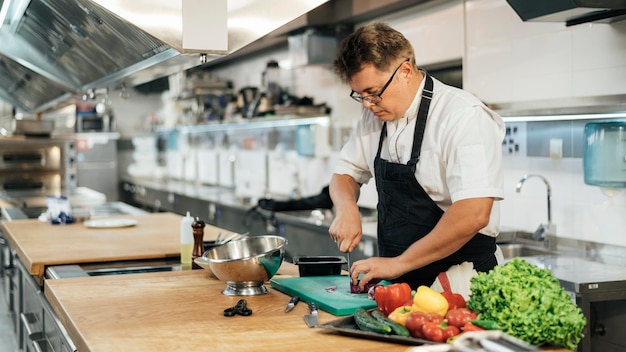 Chef masculin avec tablier, hacher les légumes