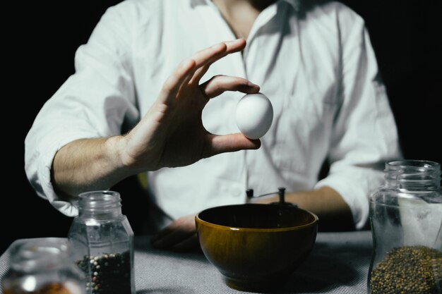 Chef masculin tenant un œuf dans sa main cuisson des œufs