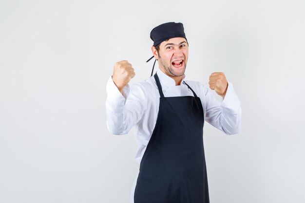 Chef masculin en uniforme, tablier debout dans la pose de boxeur et à la vue de face, énergique.