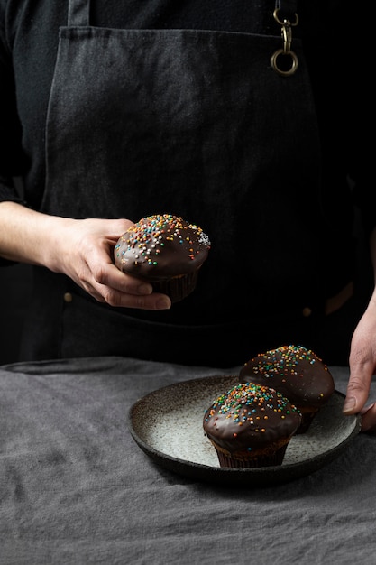 Chef pâtissier tenant la plaque avec des muffins au chocolat et des paillettes