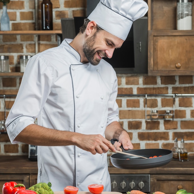 Le chef prépare la nourriture dans la poêle à frire