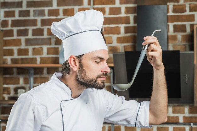 Chef souriant avec les yeux fermés sentant la soupe dans la cuisine