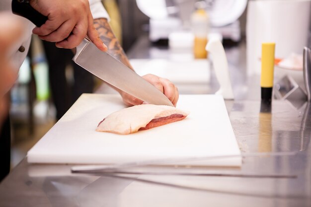 Chef tranchant le magret de canard dans le restaurant de la cuisine. préparation de la viande
