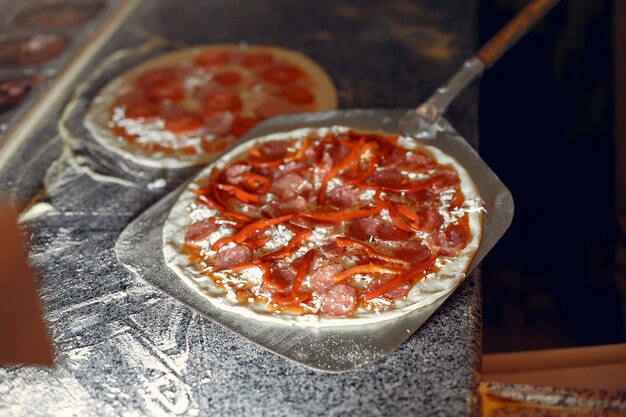 Chef en uniforme blanc prépare une pizza