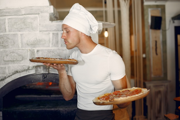 Chef en uniforme blanc prépare une pizza