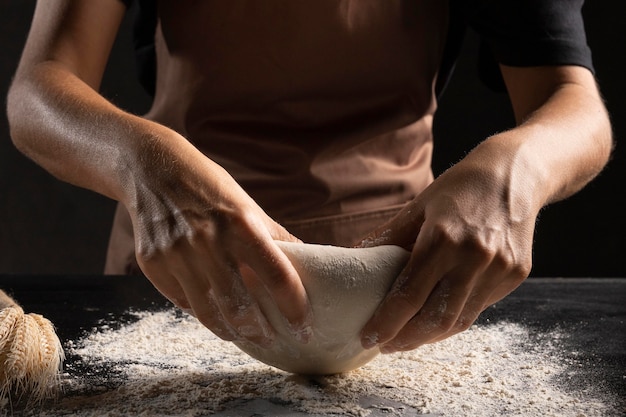 Chef utilisant de la farine pour pétrir la pâte afin qu'elle ne colle pas aux mains