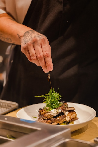 Chef versant l'assaisonnement sur le bœuf sur la plaque