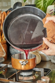 Le chef verse le liquide dans la marmite en cuivre à feu doux sur la cuisinière pour faire la sauce