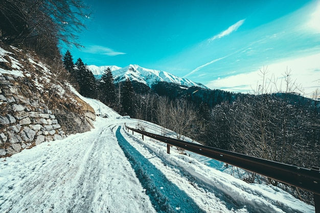 Chemin de neige au flanc d'une montagne avec des montagnes couvertes de neige