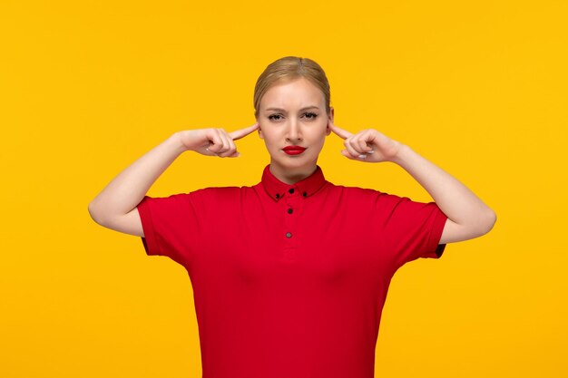 Chemise rouge jour fille blonde touchant sérieusement ses tempes dans une chemise rouge sur fond jaune