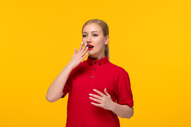 Chemise rouge jour jolie fille blonde couvrant sa bouche dans une chemise rouge sur fond jaune