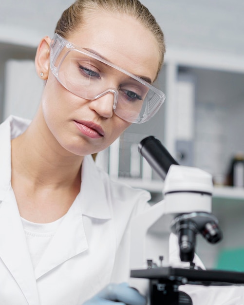 Chercheur en laboratoire avec lunettes de sécurité et microscope