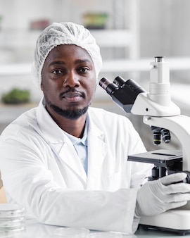 Chercheur masculin dans le laboratoire de biotechnologie avec microscope et gants