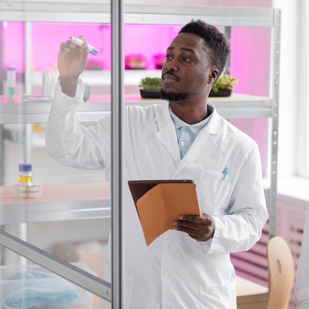 Photo gratuite chercheur masculin dans le laboratoire de biotechnologie avec tablette