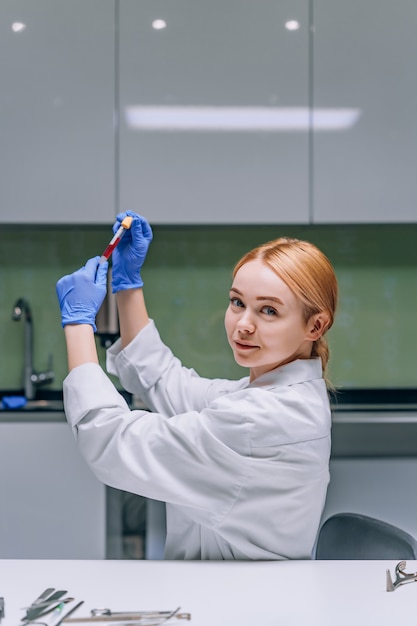 Photo gratuite chercheur médical ou scientifique féminin regardant un tube à essai dans un laboratoire.