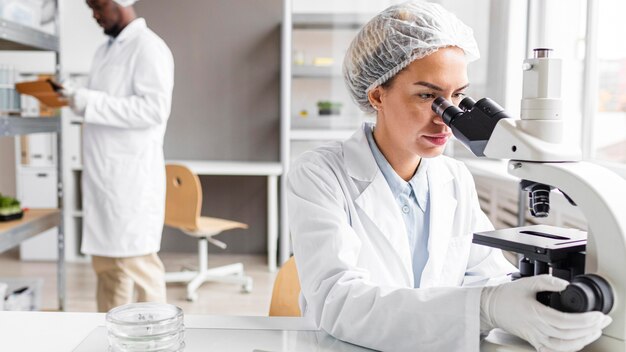 Chercheurs dans le laboratoire de biotechnologie avec tablette et microscope