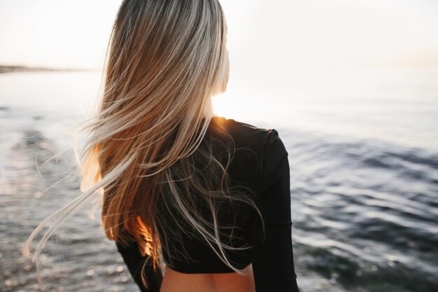 Les cheveux longs de la jeune fille se bouchent sur la mer