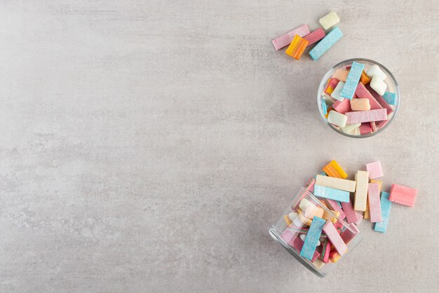 Chewing-gums colorés placés sur une table en pierre.