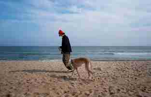 Photo gratuite chien greyhound avec propriétaire masculin à la plage