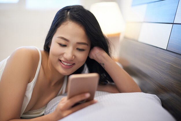 Chilling femme au lit à l'aide de téléphone