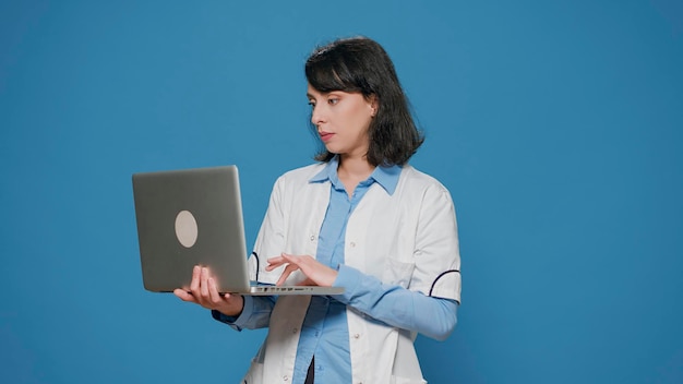 Photo gratuite chimiste en microbiologie effectuant des travaux de recherche sur un ordinateur portable en studio, naviguant sur internet pour trouver des résultats chimiques et des analyses. scientifique en chimie avec une blouse blanche utilisant une expérience informatique.