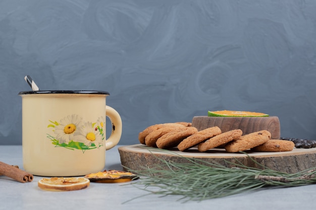 Chip cookies, tasse de thé et tranche de mandarine sur fond gris. Photo de haute qualité