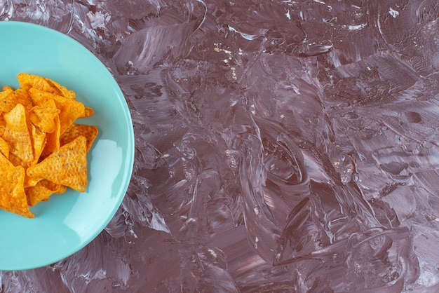 Chips épicées savoureuses sur une assiette , sur la table en marbre.