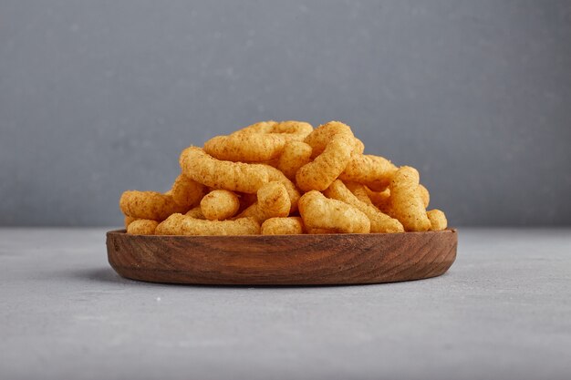 Chips de maïs aux épices dans un plateau en bois.