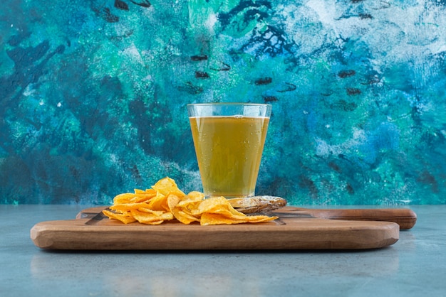 Chips, poisson et verre de bière sur une planche, sur le fond de marbre.