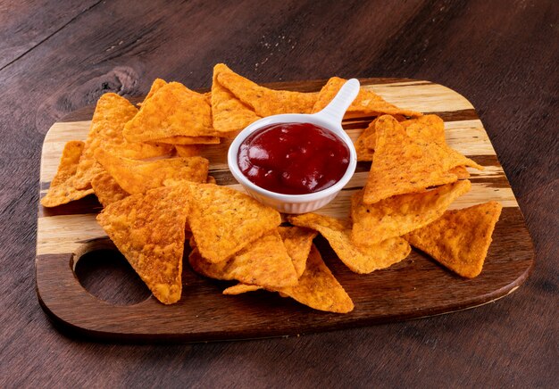 Chips vue latérale avec sause dans un bol sur une planche à découper horizontale