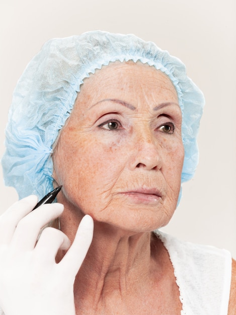 Photo gratuite chirurgien faisant une vérification de la peau d'une femme d'âge moyen avant une chirurgie plastique