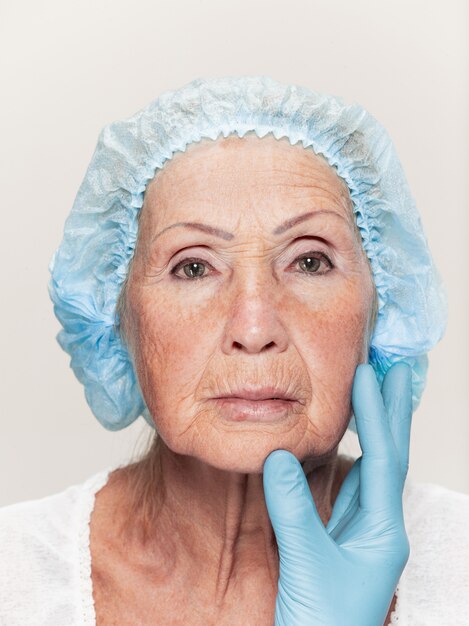 Chirurgien faisant une vérification de la peau d'une femme d'âge moyen avant une chirurgie plastique