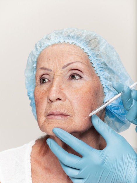 Chirurgien faisant une vérification de la peau d'une femme d'âge moyen avant une chirurgie plastique