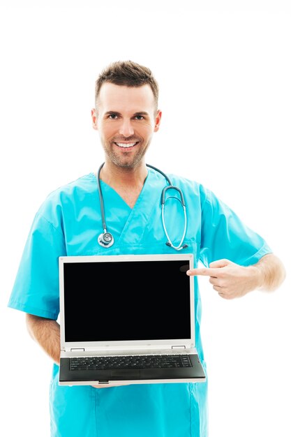 Chirurgien souriant, pointant sur un ordinateur portable