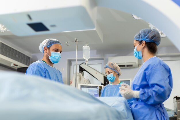 Chirurgiens avec masque chirurgical en salle d'opération à l'aide d'une machine de chirurgie guidée par image 3d