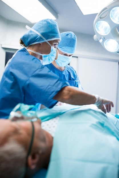 Les Chirurgiens Qui Pratiquent L'exploitation En Salle D'opération
