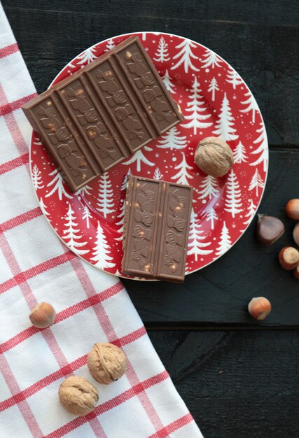 Chocolat au lait aux noix dans une assiette rouge sur la table en bois.