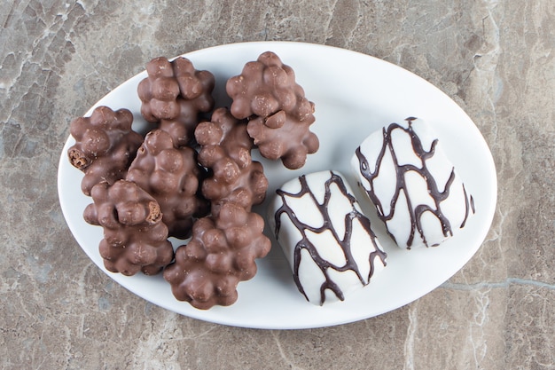 Chocolat aux noisettes et bonbons sur une assiette sur bleu.