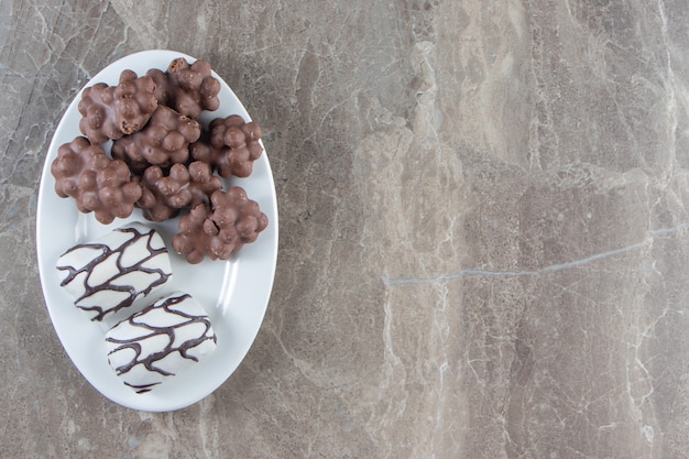 Photo gratuite chocolat aux noisettes et bonbons sur une assiette, sur le bleu.